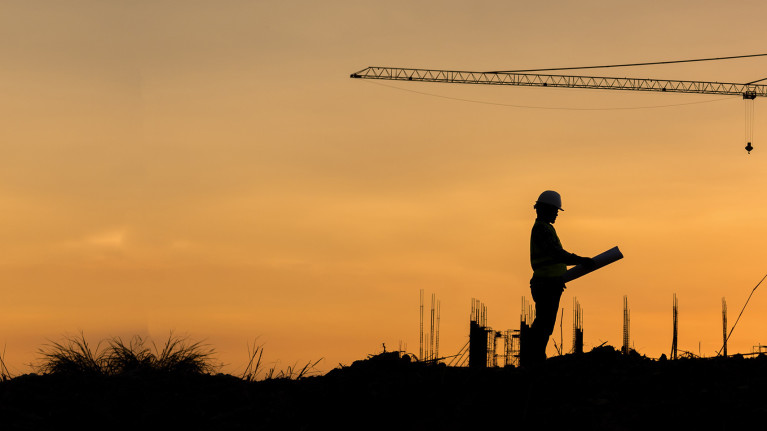 a person holding a hardhat in front of a large oil pump