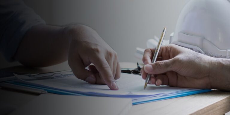 Close up shot of two people reviewing financial documents next to a construction hard hat.